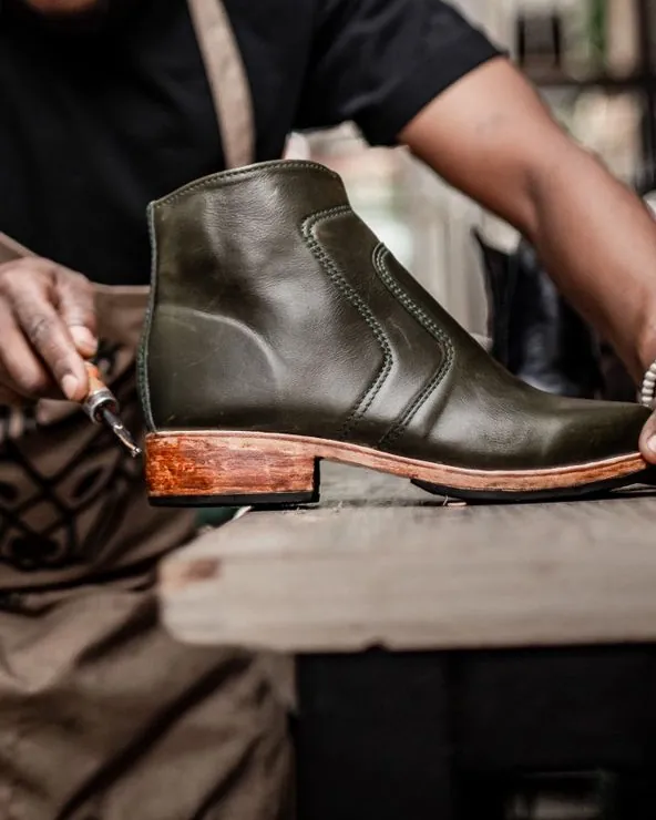 Hands at the bench, working the edge of a boot