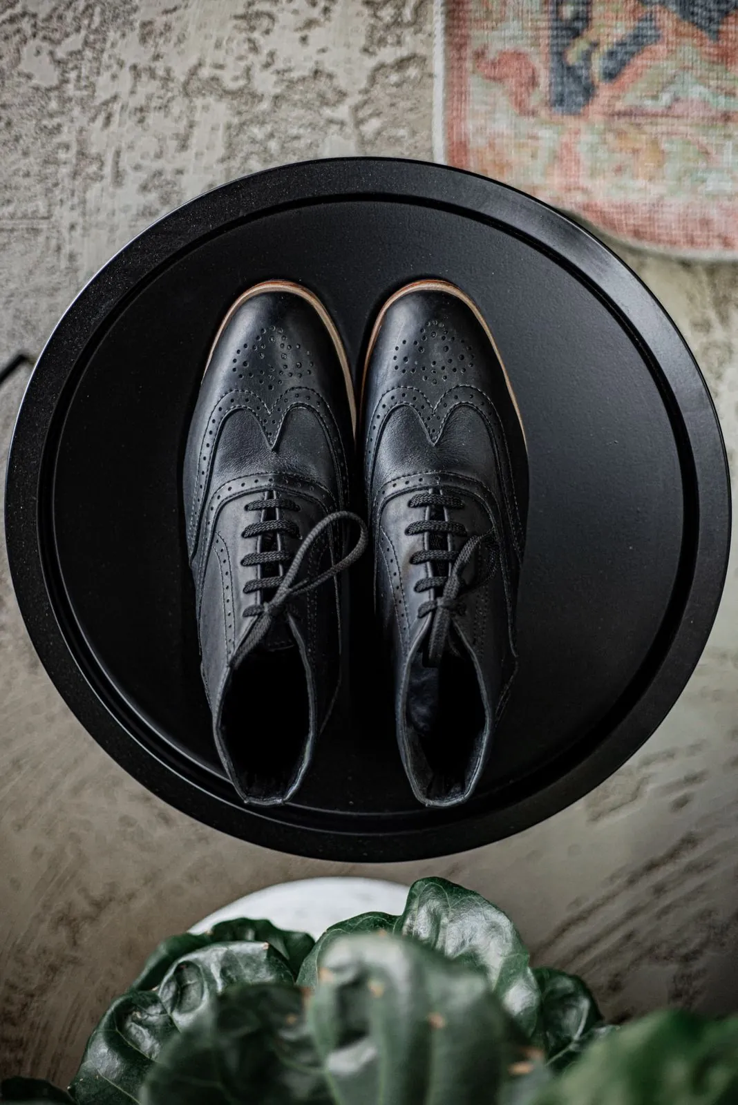 A pair of black brogue shoes on a round table in the Room, seen from above