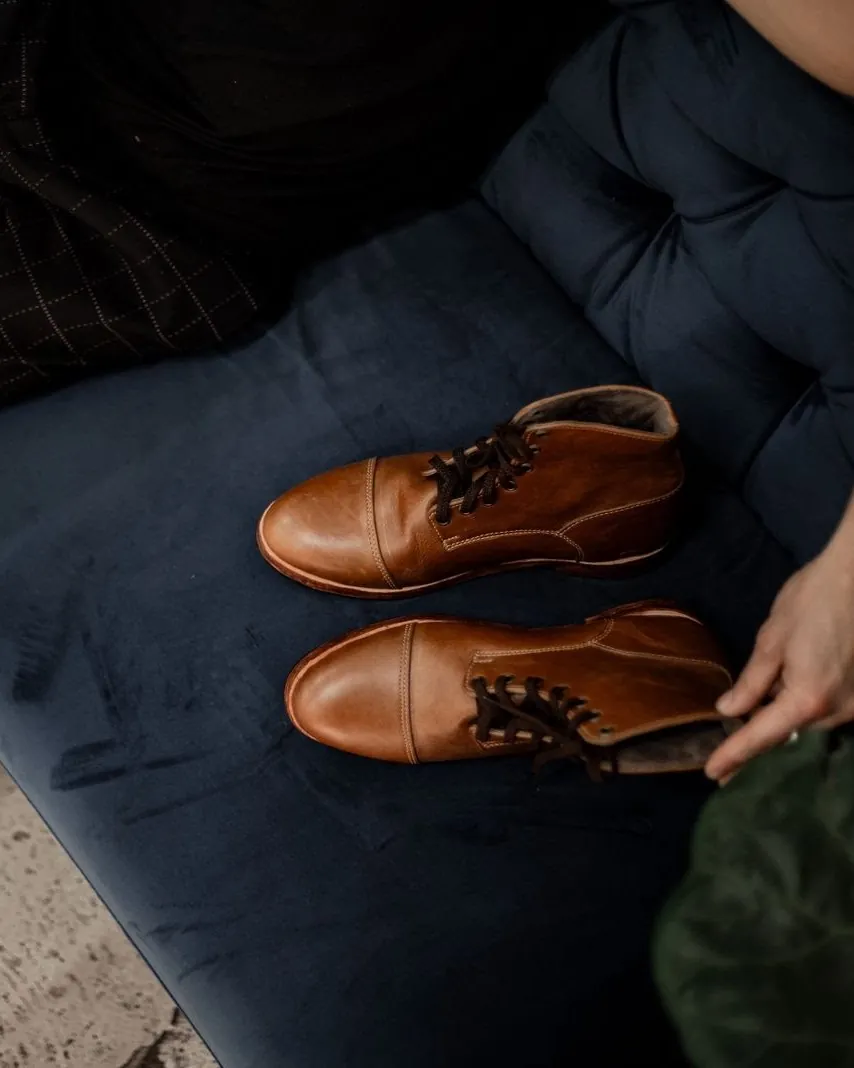 Hands setting down a tan pair on the bench seat in the Room